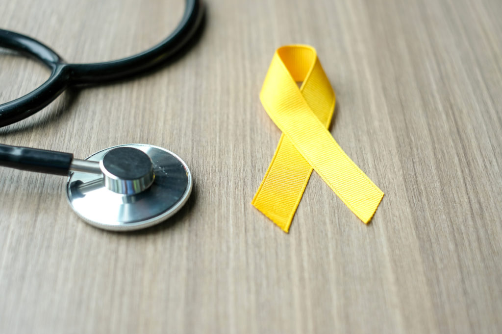 childhood cancer awareness, yellow ribbon with stethoscope for supporting people living and illness. children healthcare and world cancer day concept